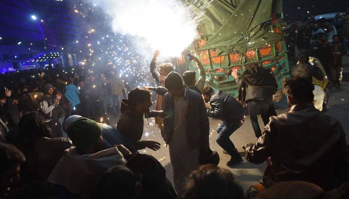 Pakistani youth enjoy the firework display during the New Year celebrations in Rawalpindi. — AFP/File