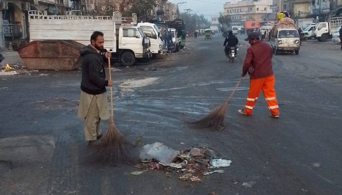 Rawalpindi Waste Mana­gement Company workers seen cleaning at a road in Rawalpindi.— Facebook@www.rwmc.org.pk/File