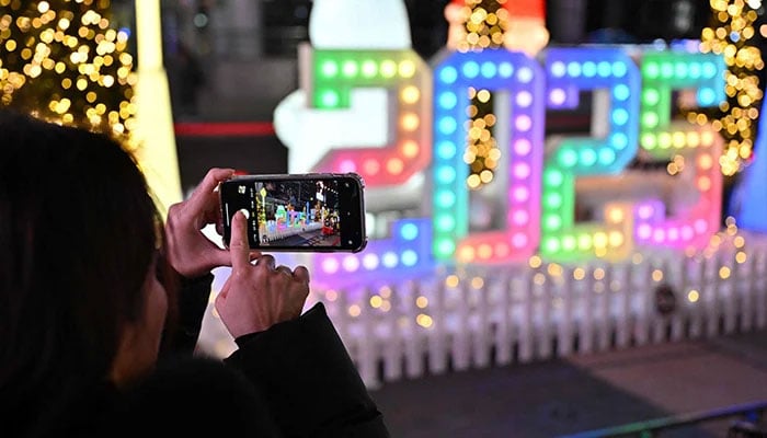 A woman takes a photo in front of a 2025 luminous sign before a countdown event to celebrate the New Year in Seoul on December 31, 2024. — AFP