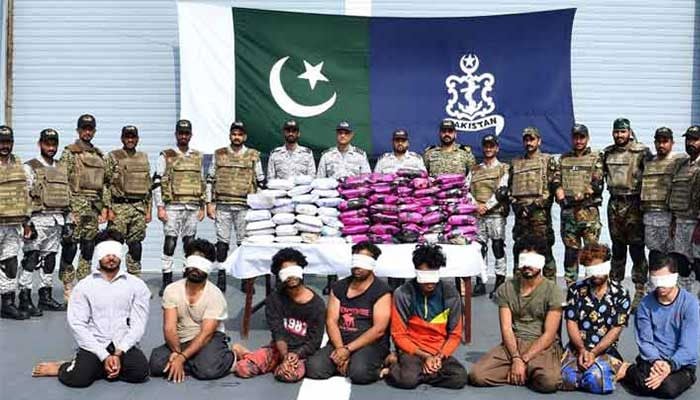 Pakistan Navy officers are seen with seized narcotics and arrested drugs smugglers with blindfolds in the front on  January 1, 2025.— Facebook@DgprNavy