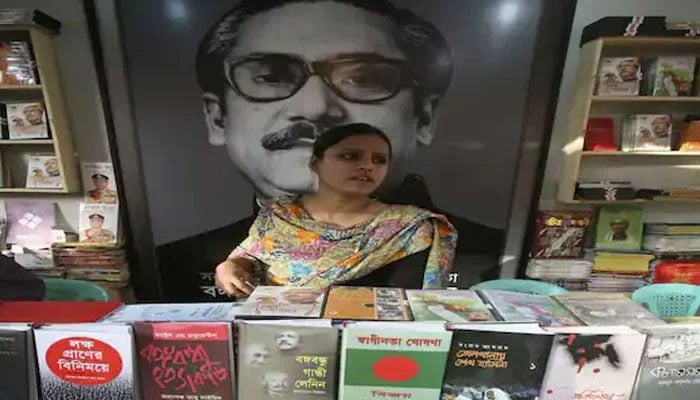 A salesperson stands in front of a picture of Sheikh Mujibur Rahman. — Reuters/File