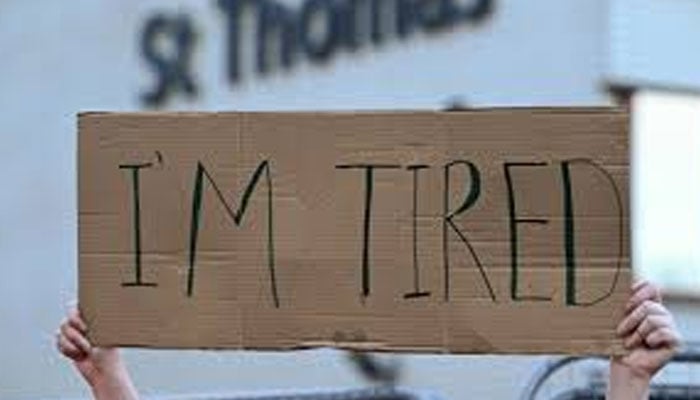 A person holding a cardboard sign of  I am tired. — AFP/File