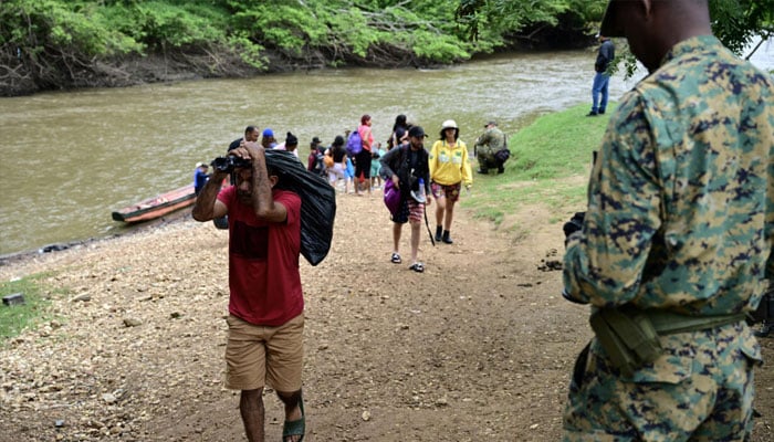 Migrants passing by a security guard. — AFP/File