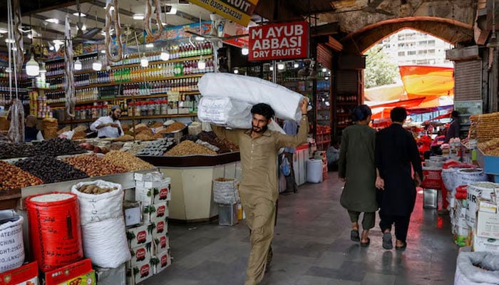 A man walks with sacks of supplies on his shoulder to deliver to a nearby shop at a market in Karachi, Pakistan June 11, 2024. — Reuters