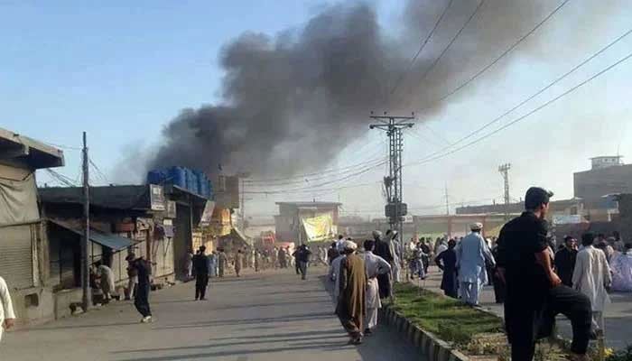 Residents gather along a road as smoke billows after twin blasts at a market in Parachinar, capital of Kurram district. — AFP/File