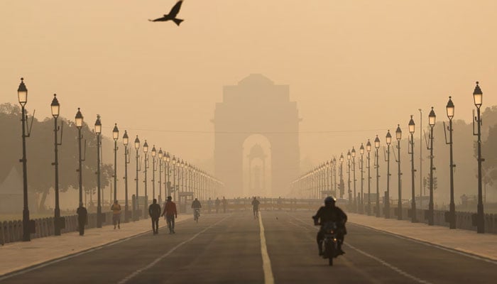 People walk on Kartavyapath near India Gate on a hazy morning in New Delhi, India, November 1. — Reuters