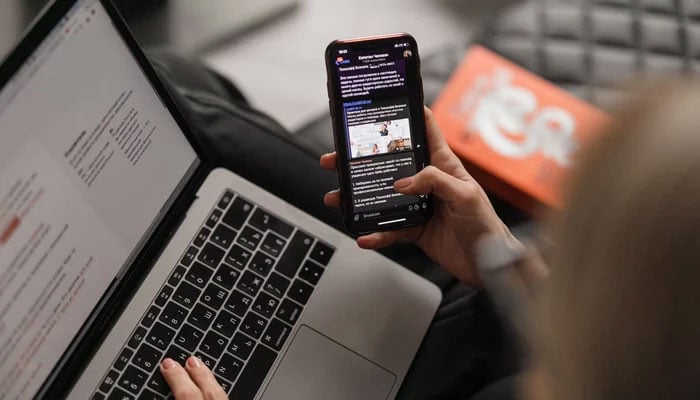 This representational image shows a person using a mobile phone with a laptop. — Unsplash/File