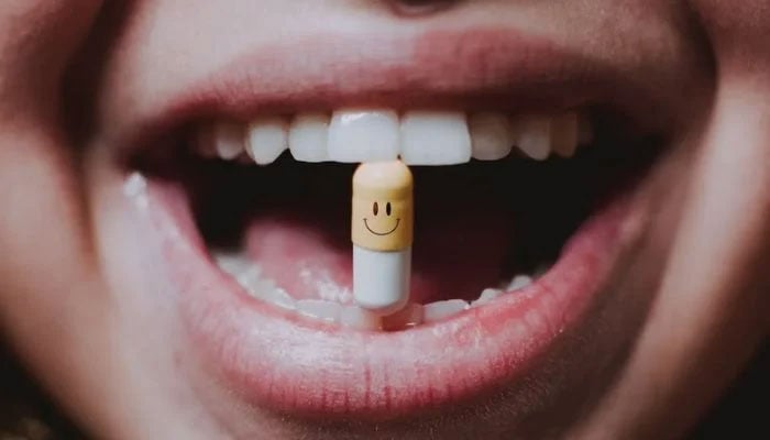 Faceless woman with a pill between her teeth.— Pexels/File