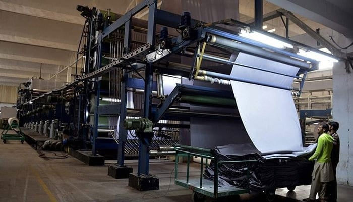 Workers operate a machine at a textile factory. — AFP/File