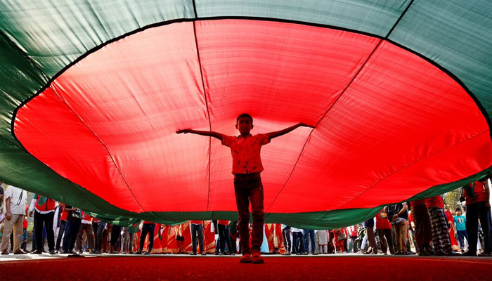 A boy poses for a picture under a massive Bangladeshi flag, during a flag rally three days ahead of the countrys 50th Victory Day anniversary, in front of the parliamentary building in Dhaka, Bangladesh, December 13, 2021.— Reuters