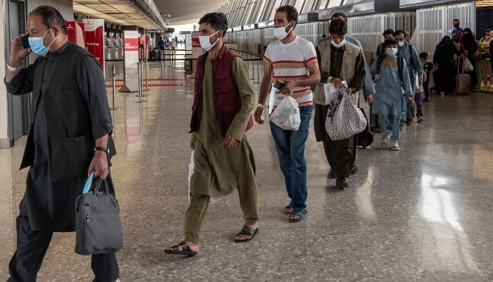 Refugees from Afghanistan being escorted to a bus after arriving at an airport. — AFP/File