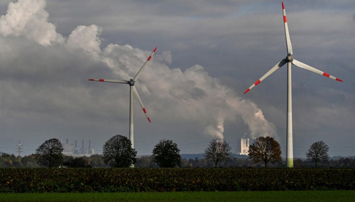 A wind turbine in front of a lignite-fired power station operated by German energy giant RWE near Neurath, western Germany . —AFP/File