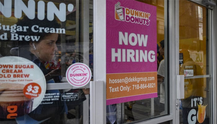 A poster can be seen outside a store labeled Now Hiring. — AFP/File