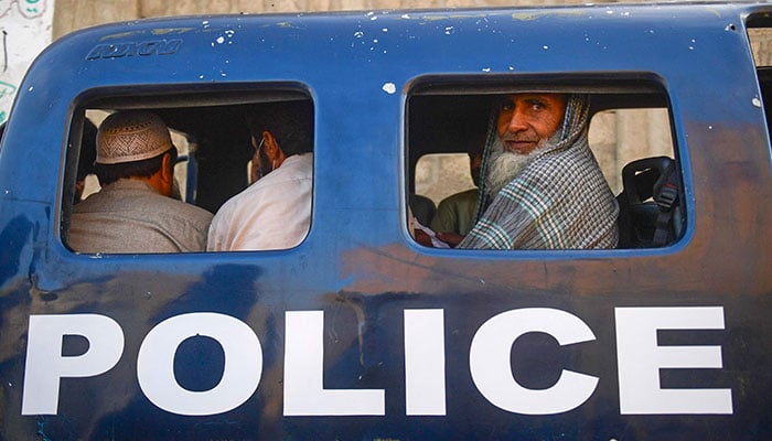 Detained Afghan refugees sit in a van during a search operation to identify alleged illegal immigrants, on the outskirts of Karachi on November 17, 2023. — AFP