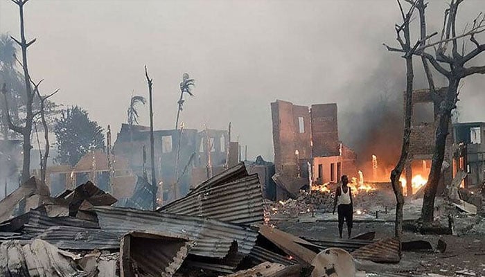 A man stands near a burning house at the site of a suspected air strike carried out by Myanmar’s military at Kyauk Ni Maw village in western Rakhine State, January 9,2025. —AFP