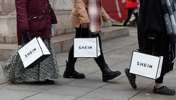 Shoppers carry bags with promotional merchandise as they visit fashion retailer Sheins Christmas bus tour, in Manchester, Britain, December 13, 2024. — Reuters