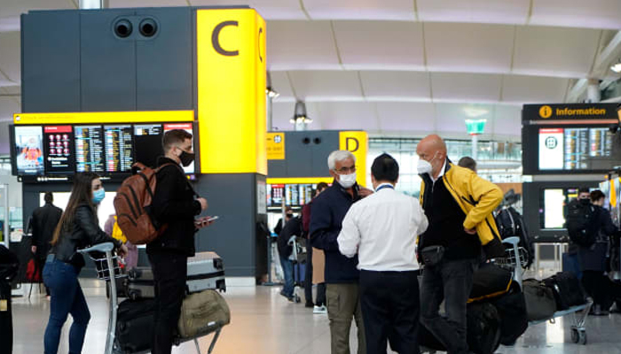 Travelers wearing a face mask or covering stand at check-in desks at Terminal 2 of Heathrow Airport in London on December 21, 2020, as a string of countries around the world banned travellers arriving from the UK. — AFP/File