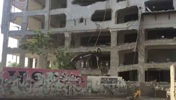 A bulldozer works on Karachis Nasla Tower. Photo: Geo News screengrab/ file