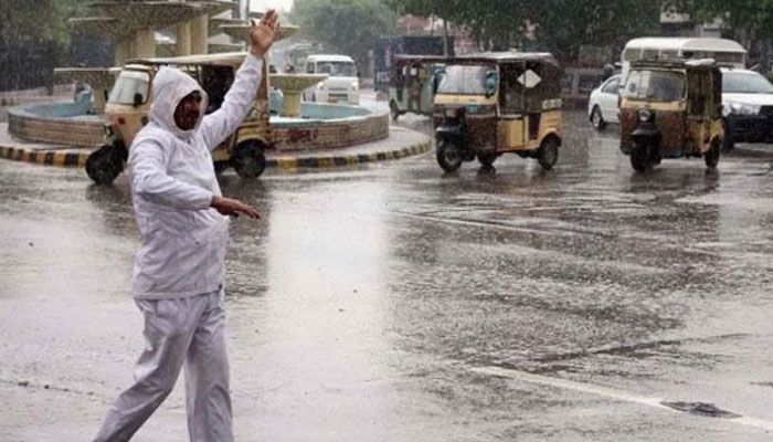 A traffic cop regulates traffic amid heavy downpour in Karachi. Photo: Geo.tv/files