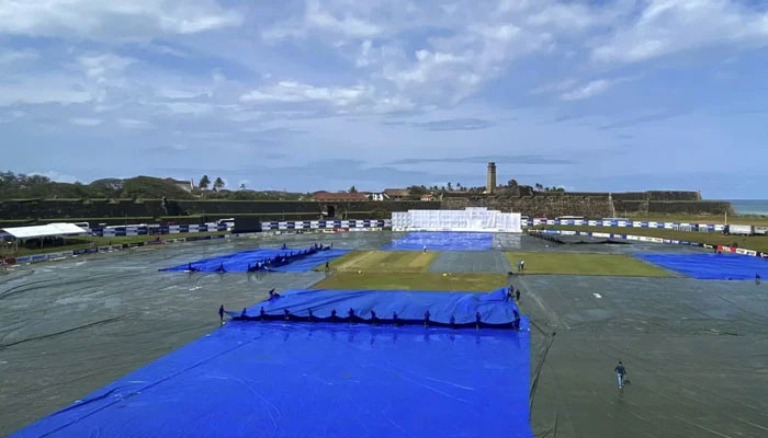 Ground staff cover the cricket pitch as rain halts play during the final day of the first cricket Test match between Sri Lanka and Pakistan at the Galle International Cricket Stadium. — Photo: ESPN cricinfo