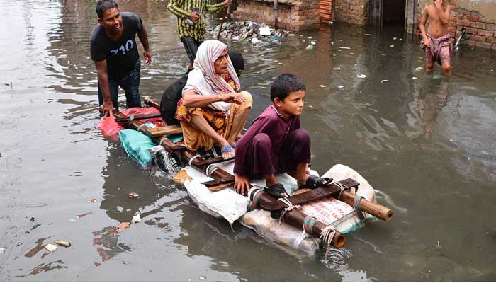 Rain-effected people are using a floating wooden raft made by a ladder at home for transportation in flooded streets at Jinah colony Latifabad in Karachi on August 19. Photo APP