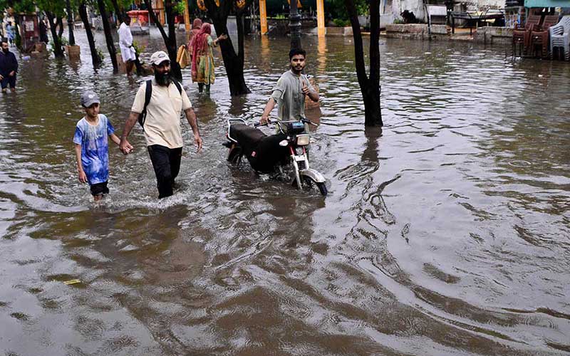 Commuters are passing through a waterlogged street. Photo: APP