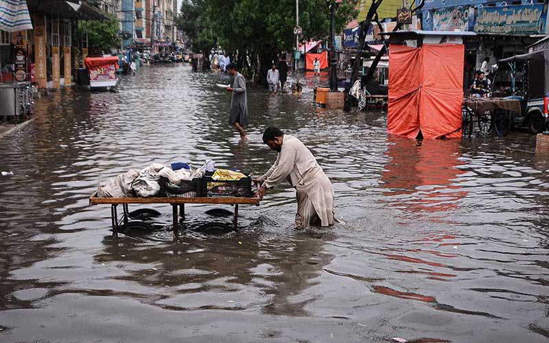 A hand cart vendor passing through rainwater at Station Road during heavy rain in the city. Photo: APP