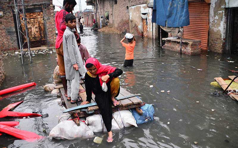 People are passing through a flooded street on a handmade boat after heavy rain in the city at jinah colony latifabad on August 19. Photo APP