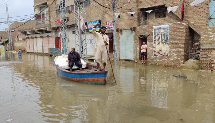 A resident makes his way by boat along a waterlogged street in Sukkur, Sindh. — AFP