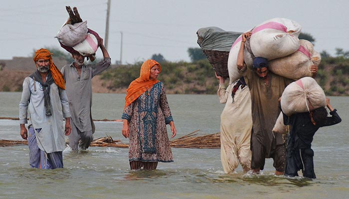 Affectees wade through flood water while journeying to relief camps in Balochistan. — AFP/Filepa