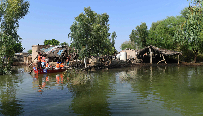 Volunteers of Charity Al-Khidmat Foundation use a boat to distribute relief material to flood-affected people at a village on the outskirts of flood-hit area of Sukkur in Sindh province on August 31, 2022. — AFP