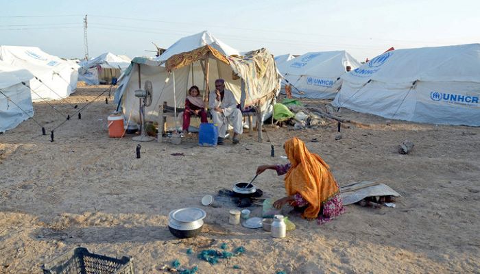 A displaced flood-affected woman cooks food for her family at a makeshift camp at Sohbatpur in Jaffarabad district of Pakistans Balochistan province on October 4, 2022. — AFP