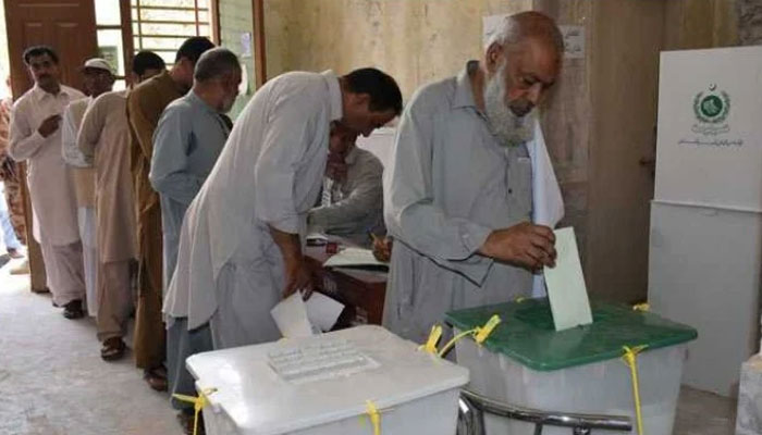 Men stand in a queue to cast their votes at a polling station in Pakistan. — AFP/ File