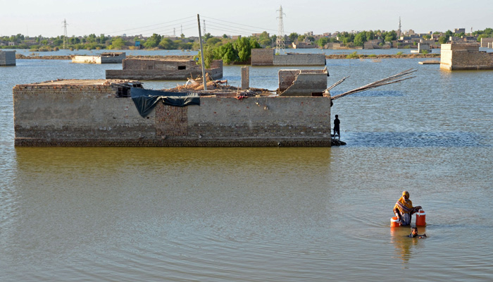 In this file photo taken on October 06, 2022, A flood-affected woman wades through the flood waters to fill drinking water at Dera Allah Yar in Jaffarabad district of Balochistan province on October 6, 2022. — AFP