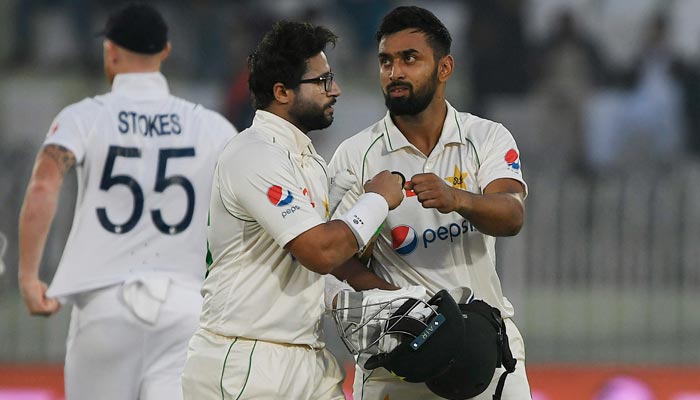 Pakistan´s Abdullah Shafique (R) and teammate Imam-ul-Haq gesture as they walk back to the pavilion at the end of the second day of the first cricket Test match between Pakistan and England at the Rawalpindi Cricket Stadium, in Rawalpindi on December 2, 2022. — AFP