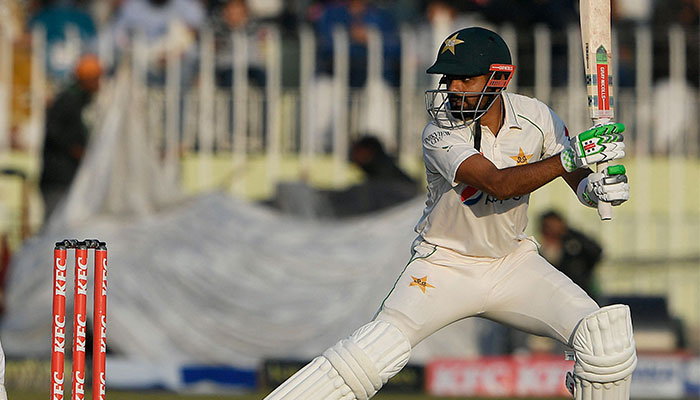 Pakistan´s captain Babar Azam (R) plays a shot as England´s wicketkeeper Ollie Pope watches during the third day of the first cricket Test match between Pakistan and England at the Rawalpindi Cricket Stadium, in Rawalpindi on December 3, 2022. — AFP