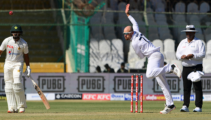 Englands Jack Leach delivers a ball as Pakistans Saud Shakeel (L) watches during the first day of the third cricket Test match between Pakistan and England at the National Stadium in Karachi on December 17, 2022. — AFP