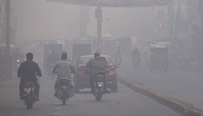 People on their way at a road during heavy fog in morning hours in Lahore. — Online/File