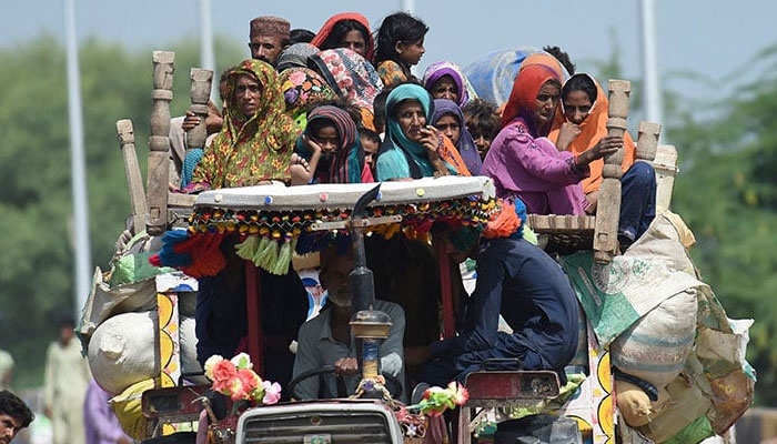 Displaced people arrive on a tractor with their belongings at a makeshift camp after fleeing from their flood hit homes following heavy monsoon rains in Sukkur, Sindh province on August 29, 2022. — AFP