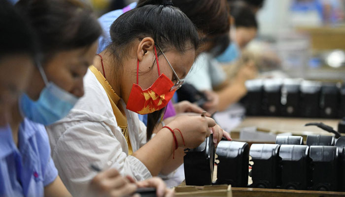 Employees work on an assembly line producing speakers at a factory in Fuyang city, in Chinas eastern Anhui province, on Sept. 30. AFP