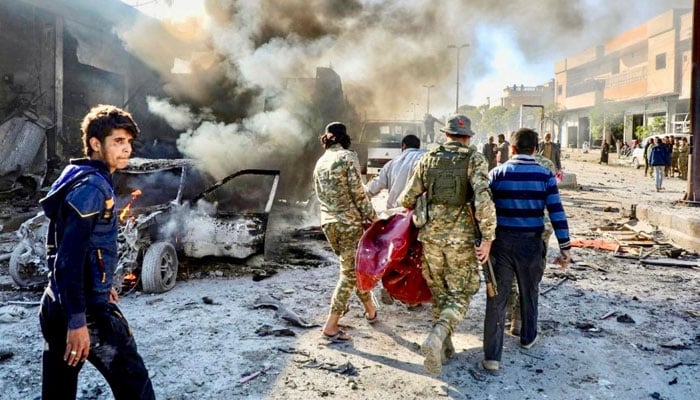 A file photo of Pro-Turkish Syrian fighters carrying away victim of a car-bomb explosion last November in Tal Abyad, which has seen several such attacks.—AFP/file