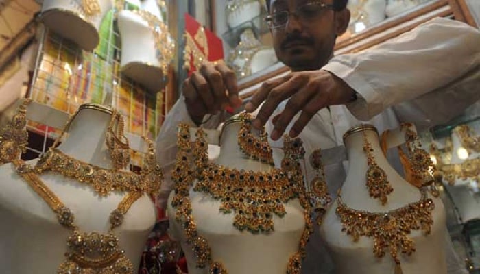 A goldsmith arranges ornaments on a manikin in his shop. — AFP/File