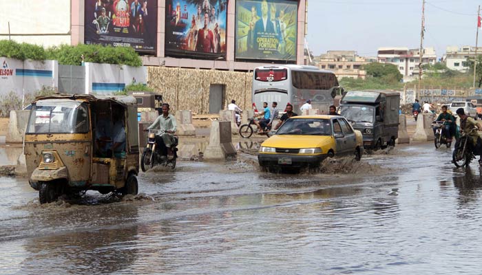 Motoristsdrive through accumulated rain water on M.A Jinnah road, Karachi on March 23, 2023. — Online