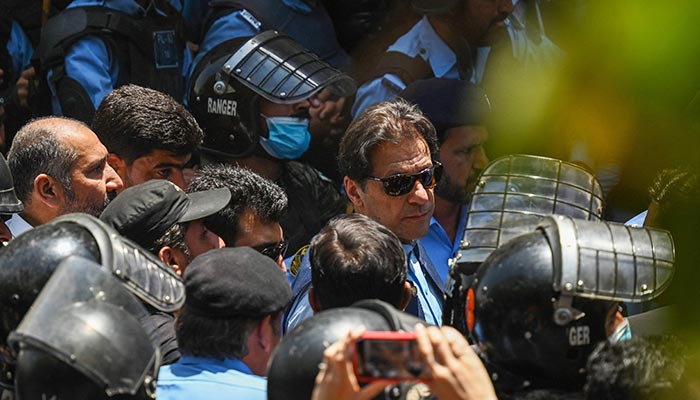 Policemen escort former Prime Minister Imran Khan (centre) as he arrives at the high court in Islamabad on May 12, 2023. — AFP