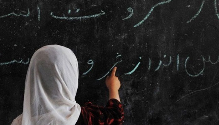 The picture shows a girl reading Urdu from a blackboard. — AFP/File