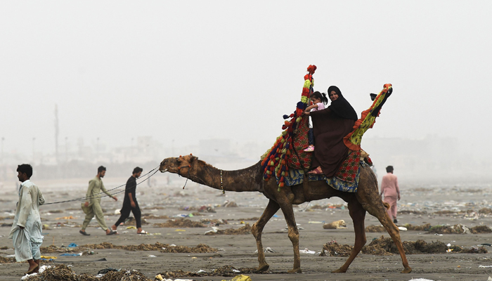 After cyclone Biparjoy makes landfall, visitors enjoy a camel ride at Sea View beach on June 16, 2023. — AFP
