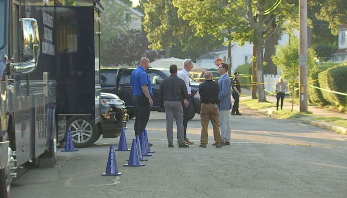 This representational picture shows residents talking together in the Nonantum neighbourhood in Newton, outside the victims home. — Twitter/@LizBatesonTV