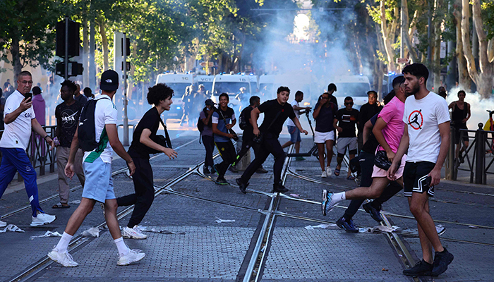 Protesters run from launched tear gas canisters during clashes with police in Marseille, southern France on July 1, 2023. — AFP