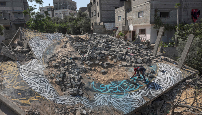 Palestinian artist Ayman Alhossary finalises Arabic calligraphy drawings on the remnants of a house destroyed by Israeli air strikes, in Beit Lahia in the northern Gaza Strip, on June 16, 2023. — AFP