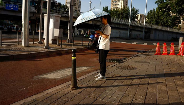 A woman carries an umbrella in Beijing, China, 04 July 2023. (EPA)